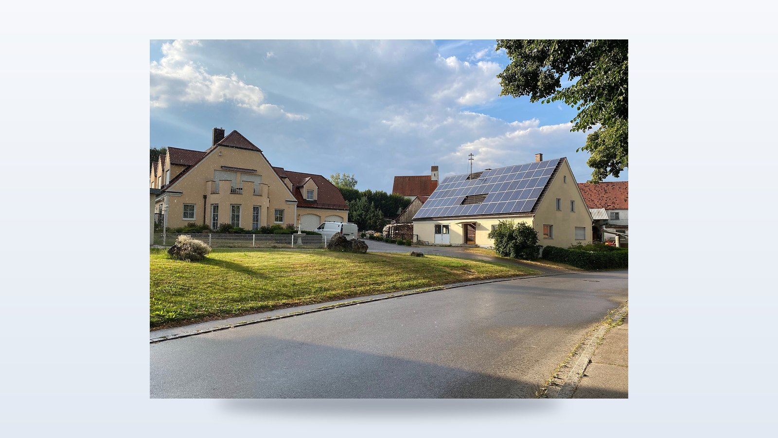 Einfamilienhaus in einem deutschen Dorf mit vollflächig mit Solarmodulen belegtem Satteldach bei Sonnenschein